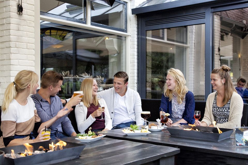 Eine Gruppe von Menschen sitzt gemütlich auf der Terrasse bei leckeren Snacks und Getränken.