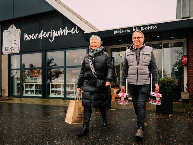 Een man en vrouw komen met hun aankopen de boerderijwinkel van Renne Streekproducten uitlopen