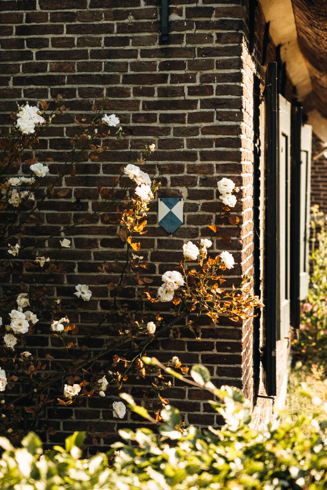 Een close up van de bakstenen muur en het rieten dak van een oude Drentse boerderij.