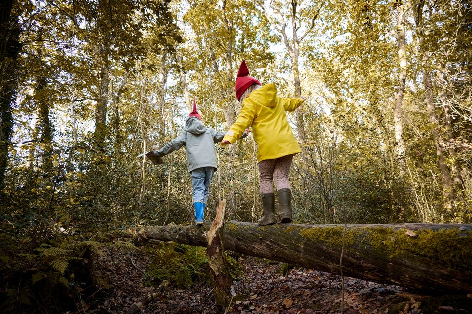 Twee kindjes met kaboutermutsjes op over een boomstam lopend in bos Elfbergen in Oudemirdum.