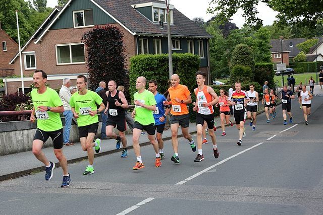 Deelnemers aan de Singelloop Woerden rennen gezamenlijk langs de singel door Woerden tijdens een lokaal hardloopevenement.