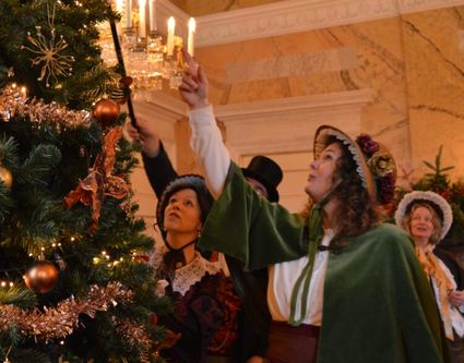 Christmas Carols van ‘The Victorians’: koorlid ontsteekt een kerstkaarsje aan in de kerstboom