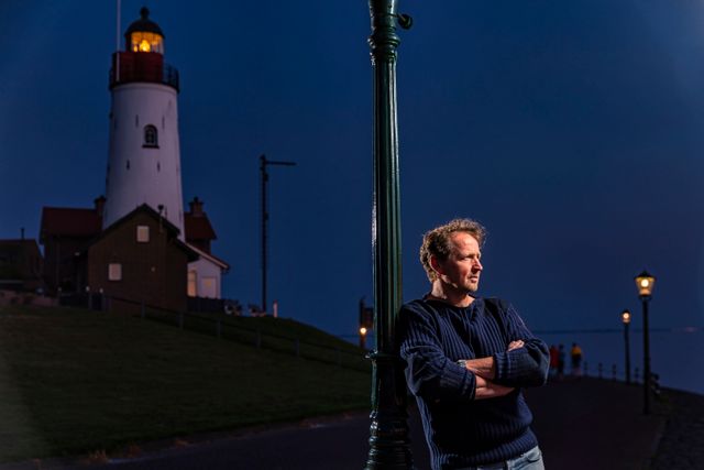Man bij vuurtoren in de avond op Urk in Flevoland