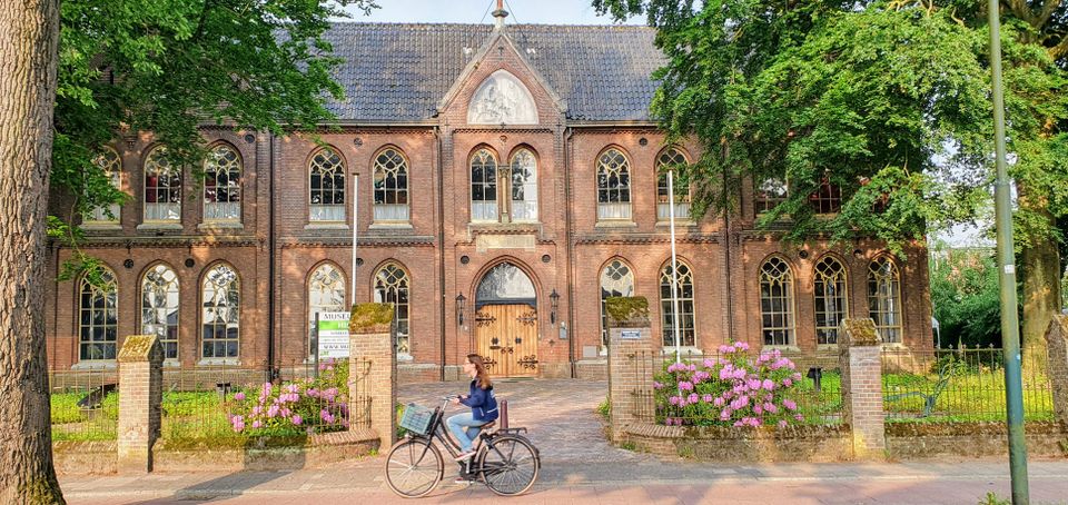 Een meisje fietst langs een oud gebouw in Soest centrum