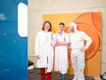 Drie mensen in labjassen en beschermende brillen bij het Leiden Kennisfestival