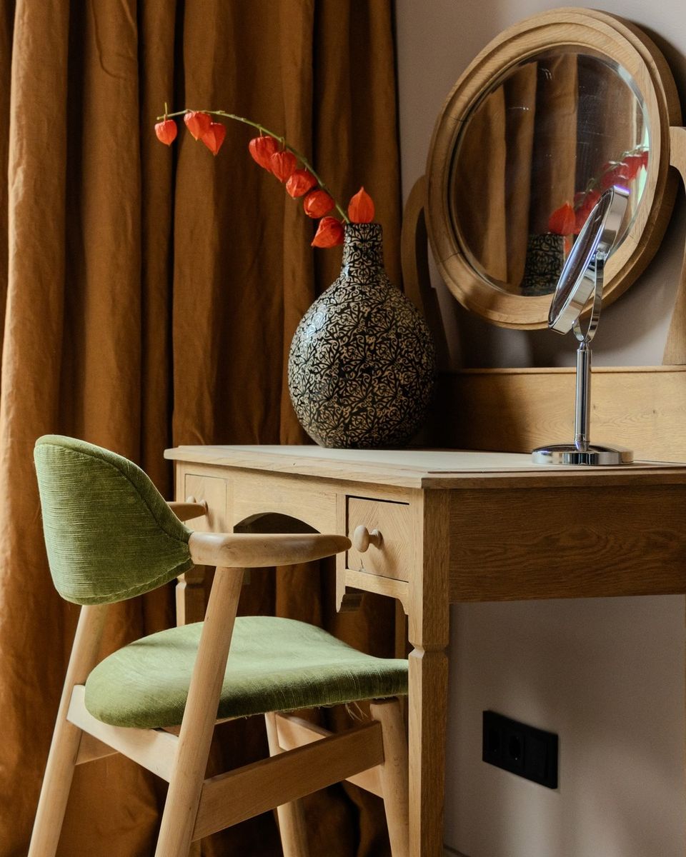 Detailfoto van een antiek bureautje met stoel en spiegel in een hotelkamer.