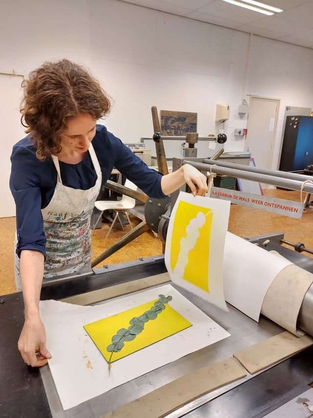 Vrouw bij de etspers onthuld haar net afgedrukte natuurdruk print.