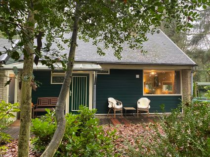 Het vakantiehuis 'Boshuisje Wateren I' vanaf de voorkant gezien. Vanuit het keukenraam rechts kijk je zo weg door de bomen. Zo wordt koken nog leuker :-)