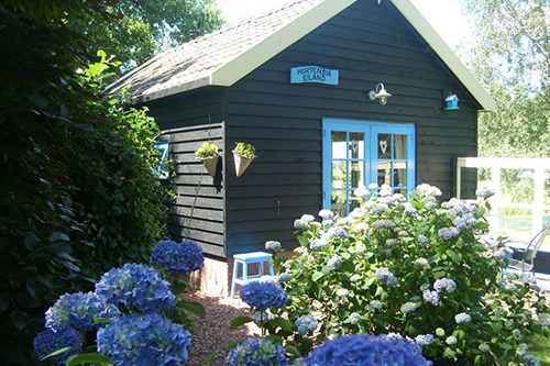 Het gastenverblijf van B&B Hortensia Eiland in het Groene Hart, omringd door bloeiende hortensia’s, sfeervolle bed and breakfast voor een rustige overnachting midden in de natuur en het groen.