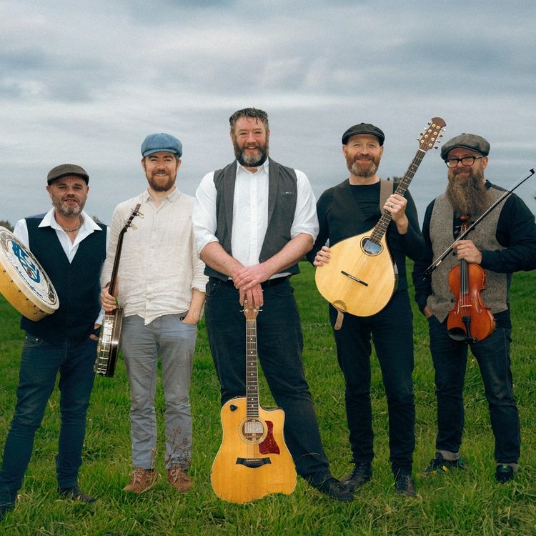 Foto van de band, bestaande uit 5 heren met pet op het hoofd. Ze staan in een weiland met hun muziekinstrumenten.