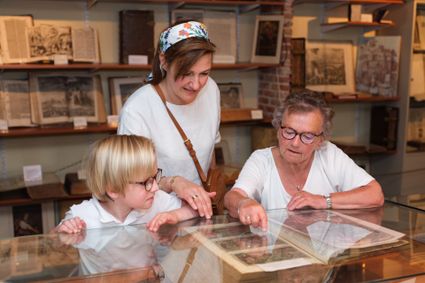 Twee volwassenen en een kind zijn in Bijbelmuseum Leerdam en kijken naar een boek.