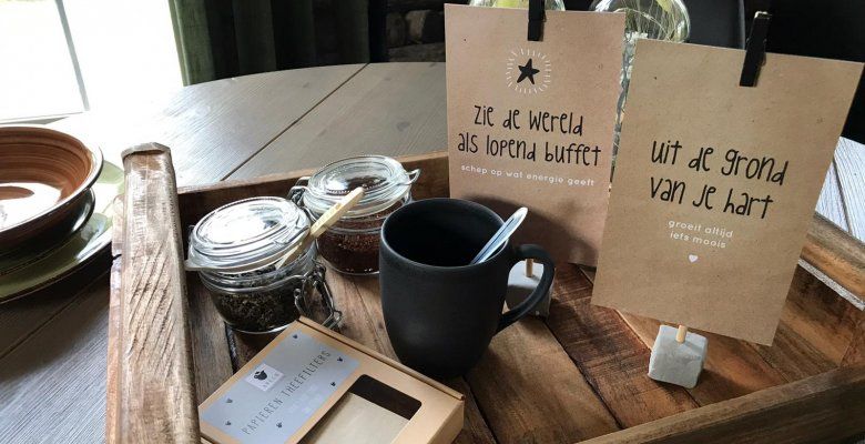 Detailfoto van een dienblad met koffiekopje en standaardjes met inspirerende teksten.