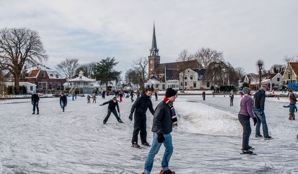 Schaatsen op het ijs met kerkje op de achtergrond