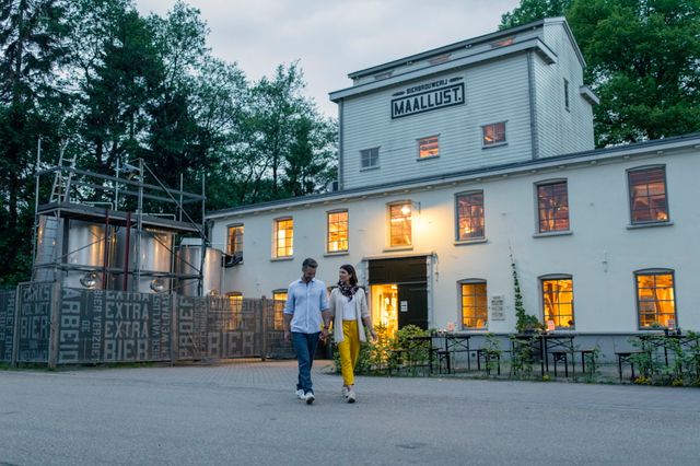 Een stel loopt in de schemering voor bierbrouwerij Maallust langs.