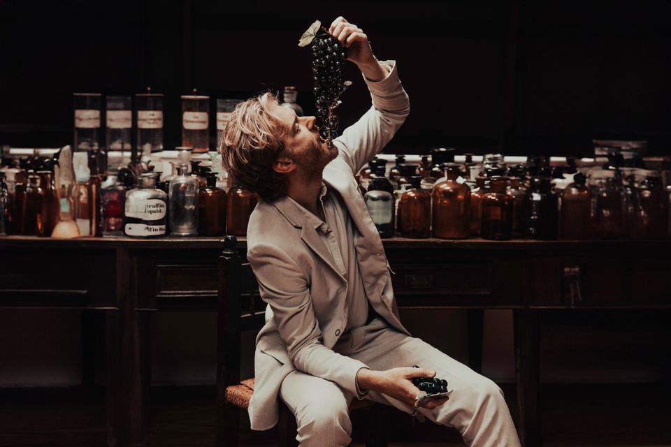 Baer Traa in een licht pak tijdens een sfeervolle fotoshoot aan een bar.