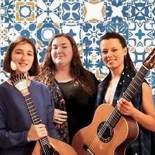 Foto van drie vrouwelijke muzikanten met gitaar voor Portugese tegeltjeswand.