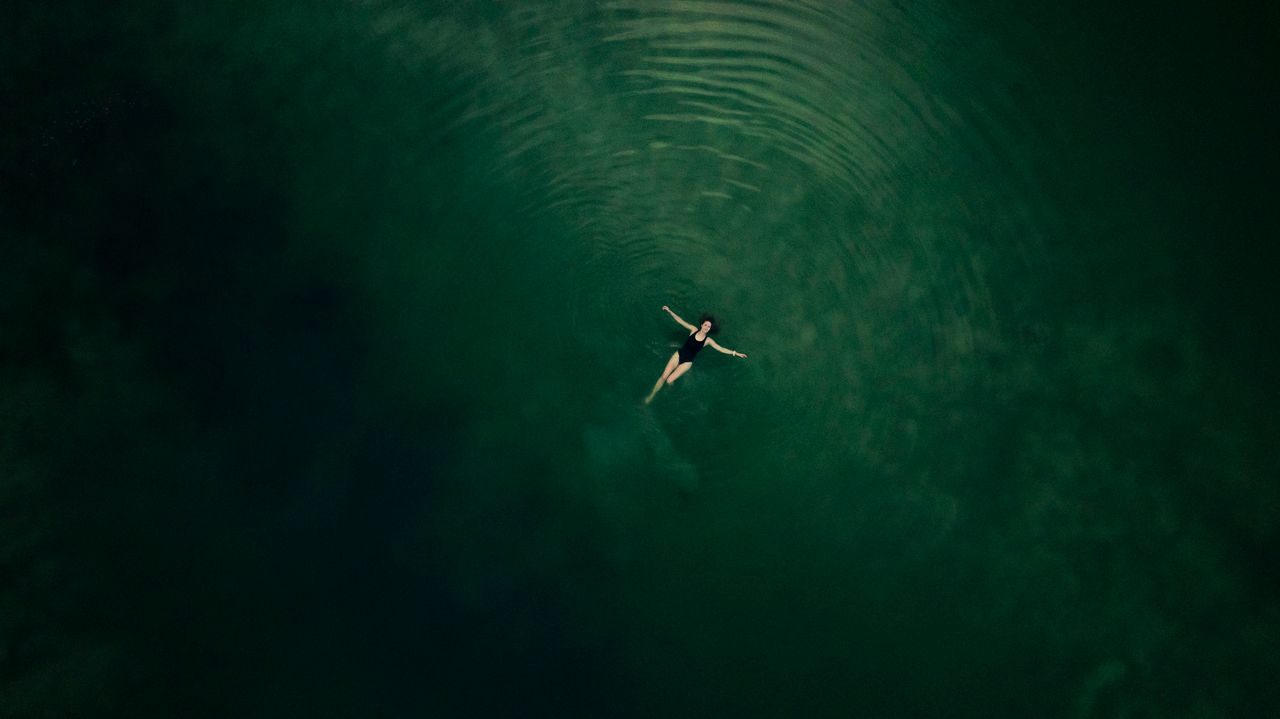 Dronebeeld van een vrouw in een zwemplas.