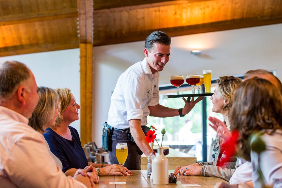Een groep mensen die heerlijk geniet van een diner bij La Trappe.