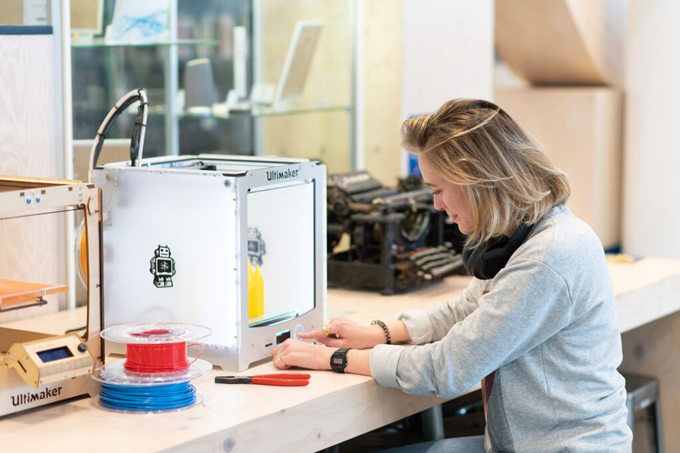 Een jonge vrouw zet een 3D-printer aan