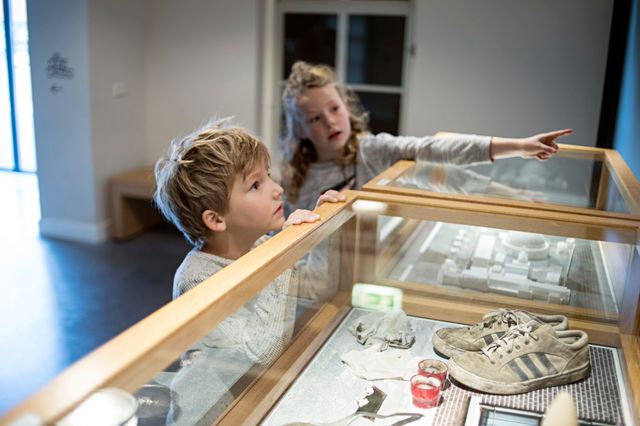 "Ein Junge und ein Mädchen schauen sich die ausgestellten Stücke im Gefängnismuseum an."