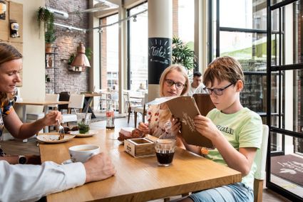 Kinderen zitten in een restaurant iets uit te zoeken.