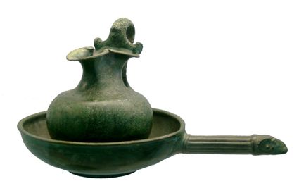 Bronzen Romeinse schaal. De steel van de schaal loopt uit in een ramskop.