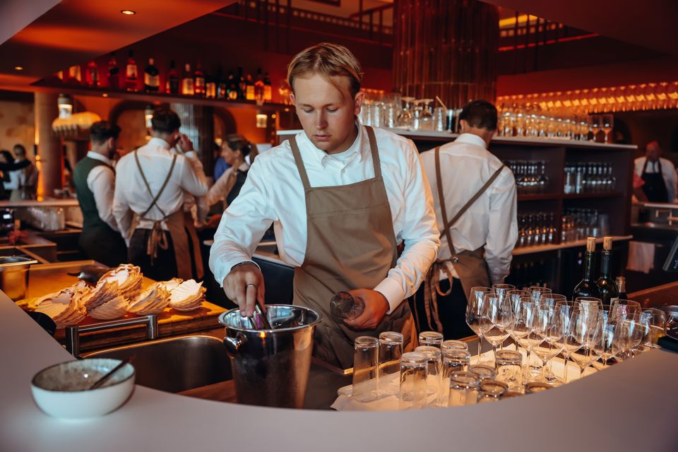 Hotel Van der Valk Woerden, Woerden, Groene Hart, bediening achter de open bar met glazen, wijn en verse gerechten in een sfeervol en modern restaurant.