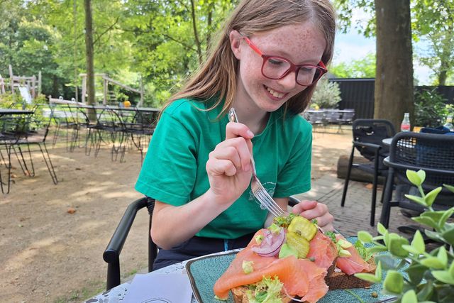 Dochter van Ellen aan het lunchen aan een houten tafel bij de Zwammenberg in de Moer.