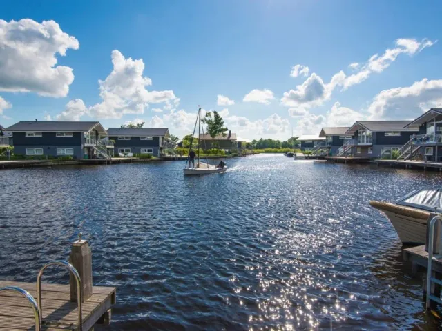 Een zeilbootje op het water tussen de vakantiehuisjes bij Landal Waterpark Sneekermeer in Terherne.