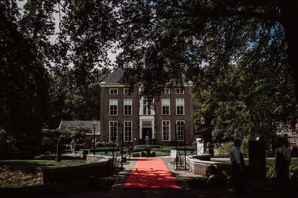 Een chateau met toegangspoort waar een rode loper voor ligt.