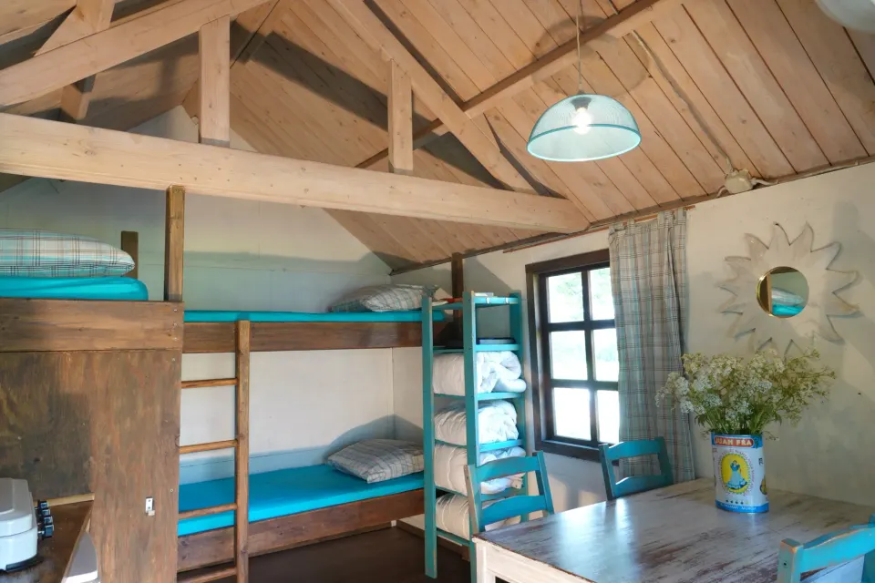 De binnenkant van een trekkershut met onder andere drie bedden en een tafel bij Welgelegen in Workum.