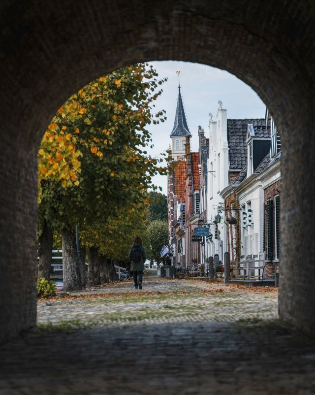 Een doorkijkje in Sloten met een wandelende vrouw vanachter gefotografeerd.