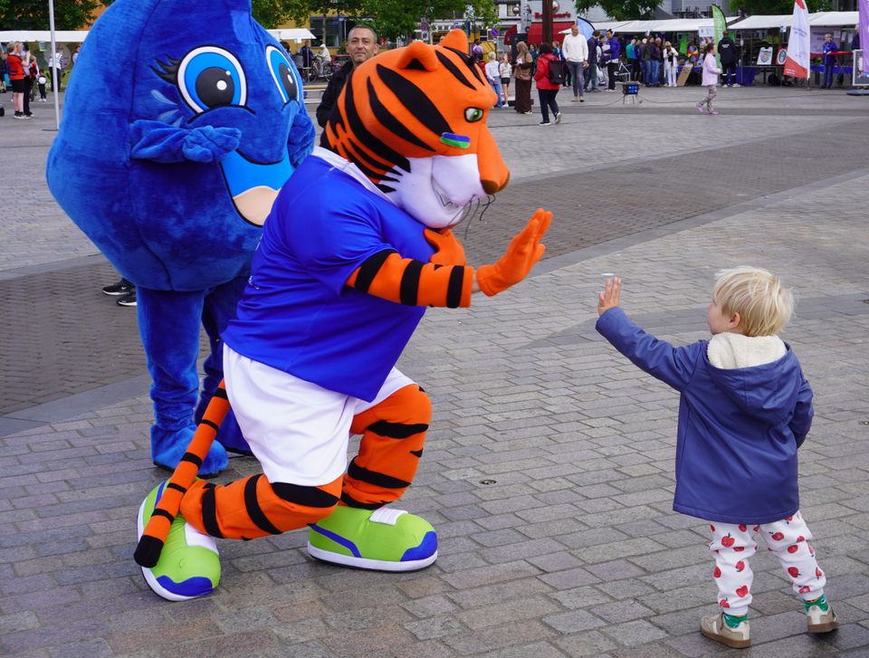 Peuter geeft een boks aan mascotte-tijger