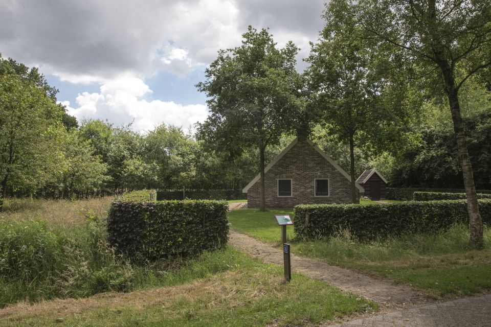 Een klein huisje op een grasveld omringd door bomen.