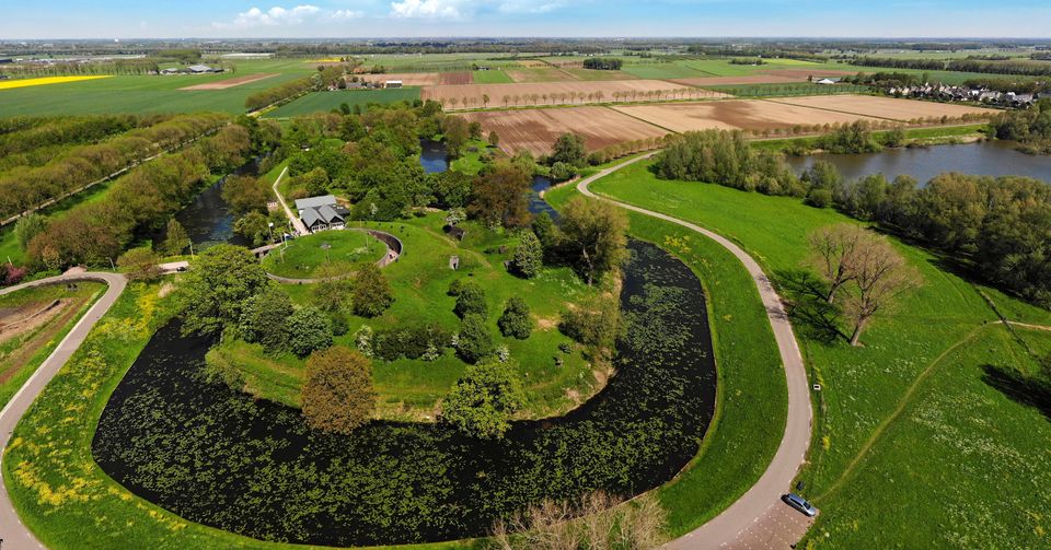 Een groen overgroeid fort met fortgracht gefotografeerd vanuit de lucht.