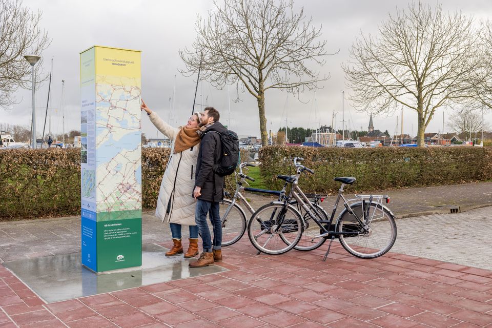 Stel met fietsen kijkt naar het Toeristisch Overstap Punt in Woudsend.