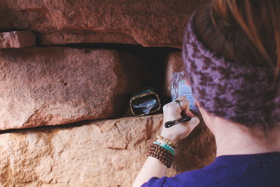 Eine Teilnehmerin findet einen Geocache in einer Steinmauer.