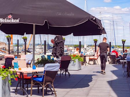 Terras met parasol en tafels en stoelen.