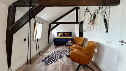 Binnenkant van de B&B met een twee persoons bed en twee stoeltjes.