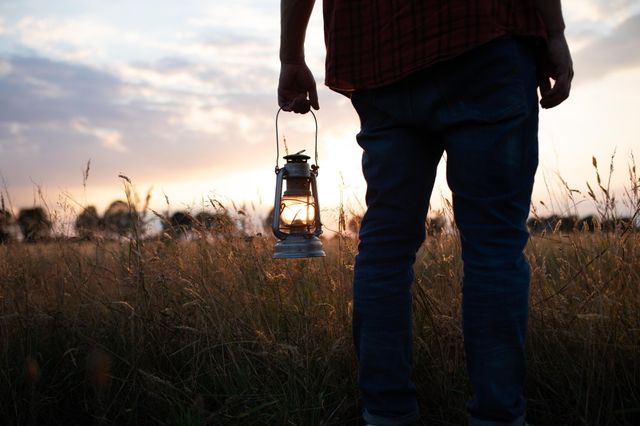 Een man staat in een korenveld met een lantaarn in zijn hand.