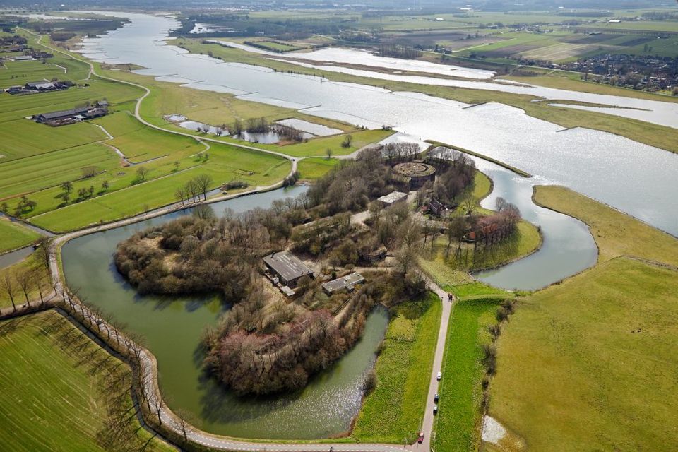 Een bakstenen fort omgeven door bomen en planten, gelegen aan een rivier.