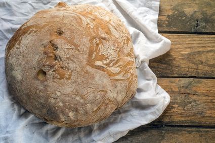 Rond ambachtelijk brood met krokante korst van Echte Bakker John Treur in Oudewater, vers gebakken en gepresenteerd op houten tafel