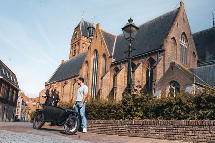 Historische kerk Grote of Sint-Michaëlskerk in Oudewater, Groene Hart. Bezoekers met bakfiets op de straat voor de monumentale gotische kerk in de historische binnenstad, populair voor fietsen, wandelen en stedentrips.