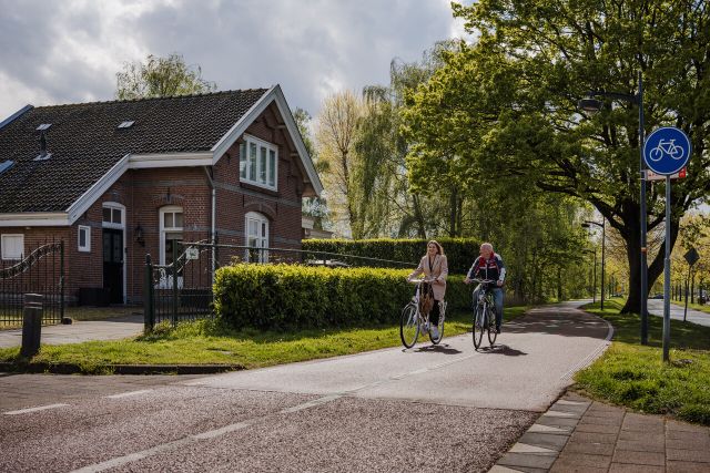 Two cyclists on the bike path next to a former guardhouse.