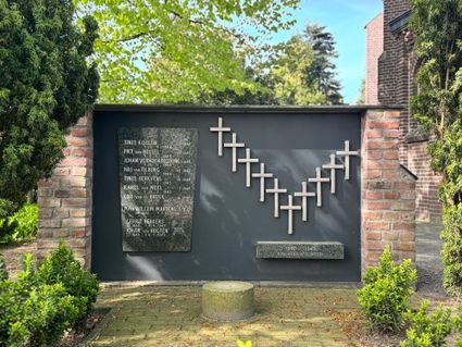Een oorlogsmonument met aan de linkerzijde een stenen plaquette met 10 namen van oorlogsslachtoffers van de 2e wereldoorlog. Aan de rechterzijde zijn 10 kruisjes geplaatst in een 'V' vorm.