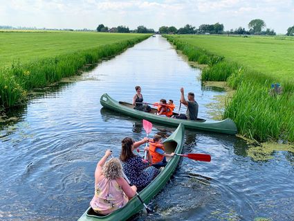 Kanoactiviteit bij Boerderij De Boerinn in Kamerik, Groene Hart. Gezinnen varen met kano’s door een smalle poldervaart tussen groene weilanden, populair familie-uitje, buitenactiviteit en dagje uit op het water in het Utrechtse polderlandschap.