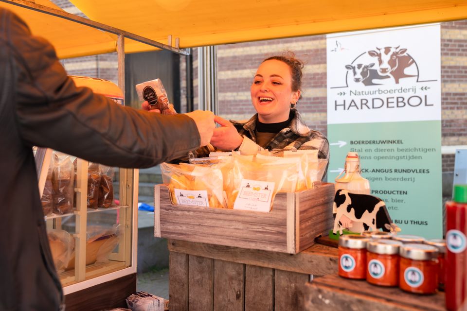 Een deelnemer van de Laag Hollandse Makersmarkt verkoopt iets aan een klant.