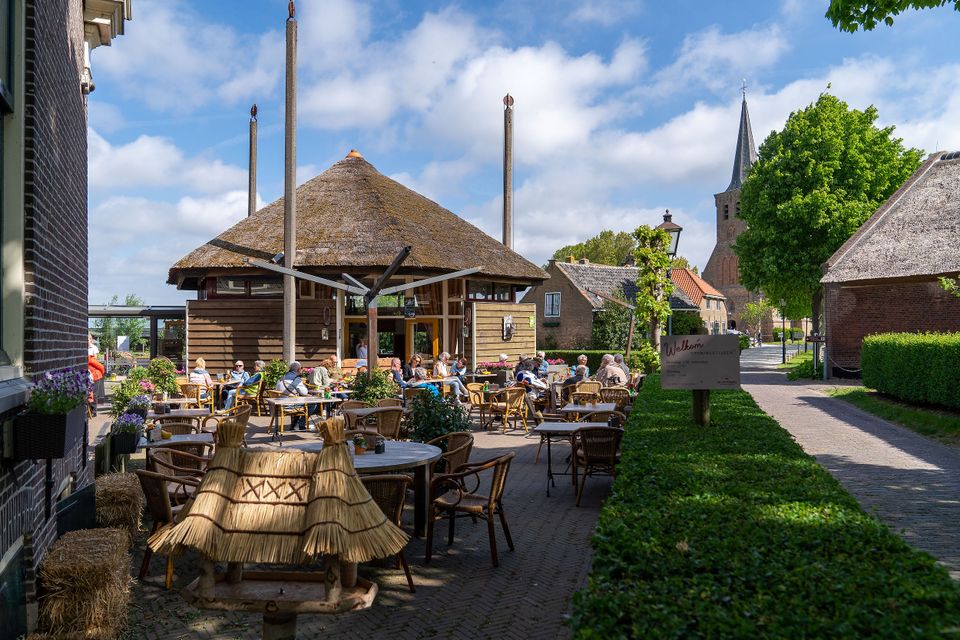 Mensen ziitend op een zomers terras in 't Woudt vlakbij Delft