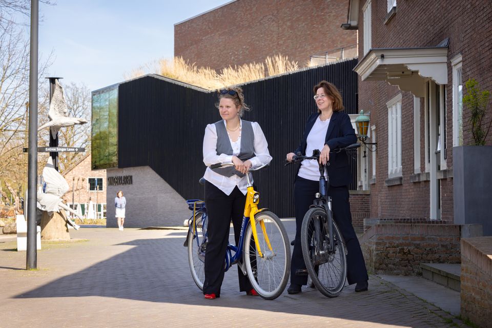 Twee fietsers staan op de stoep voor Singer Laren.
