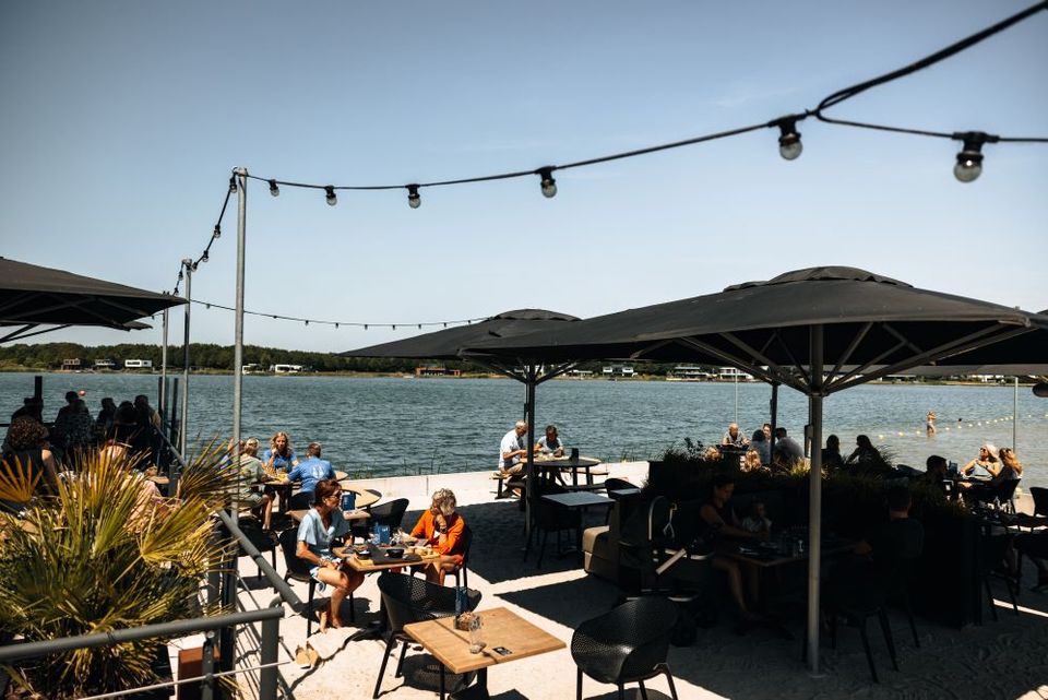 Eine Terrasse voller Menschen mit Sonnenschirmen und Lampen.
